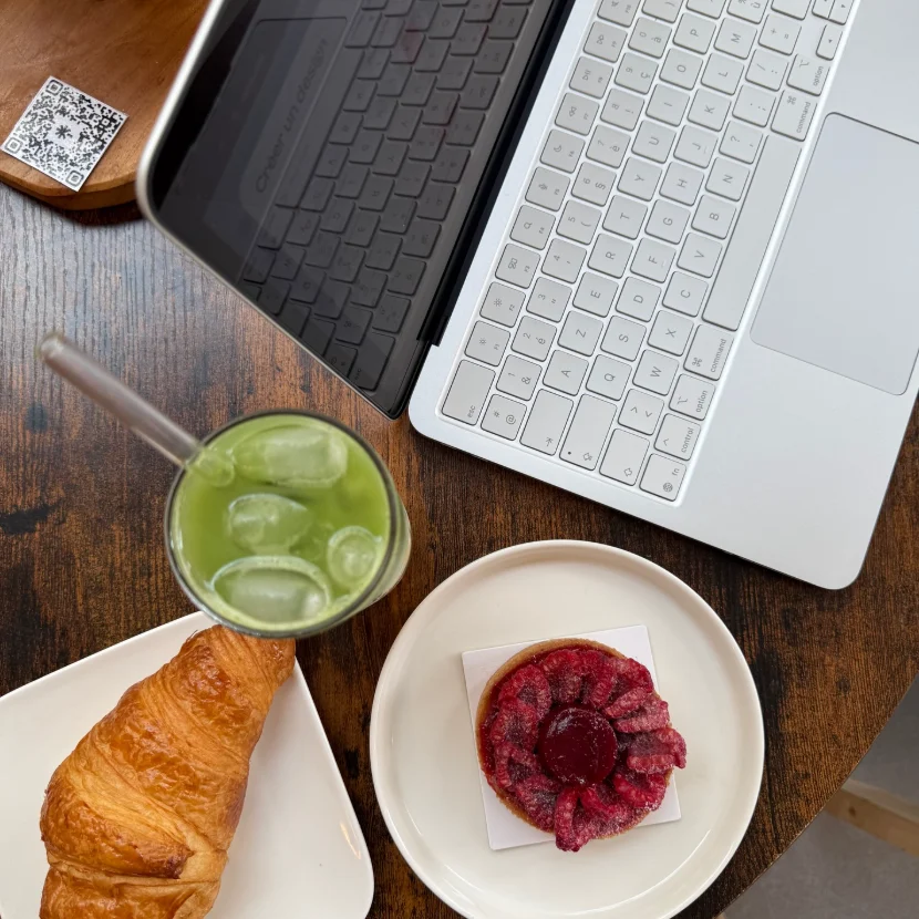 Matcha glacé, croissant et tartelette framboise à côté d'un ordinateur portable