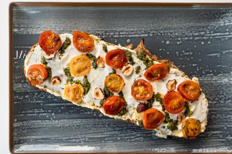 Toast méditerranéen : stracciatella, pesto, tomates confites, noisettes